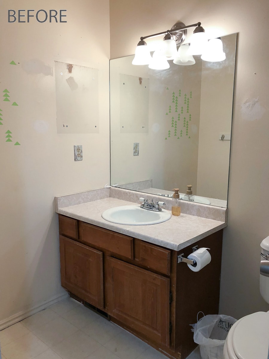 Old guest bathroom with oak builders grade vanity, large wall mirror and ugly off-white walls. 