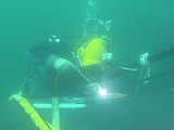 Diver wearing a diving helmet is welding a repair patch on a submarine